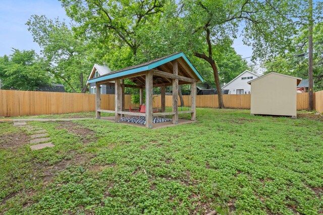 view of yard featuring a fenced backyard, a storage unit, an outbuilding, and a gazebo