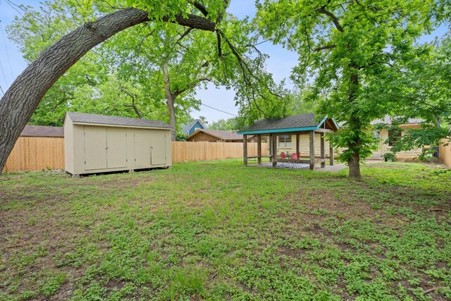 view of yard featuring a fenced backyard, a storage unit, and an outdoor structure