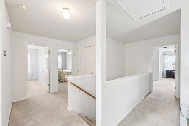 hall with carpet flooring, baseboards, and an upstairs landing