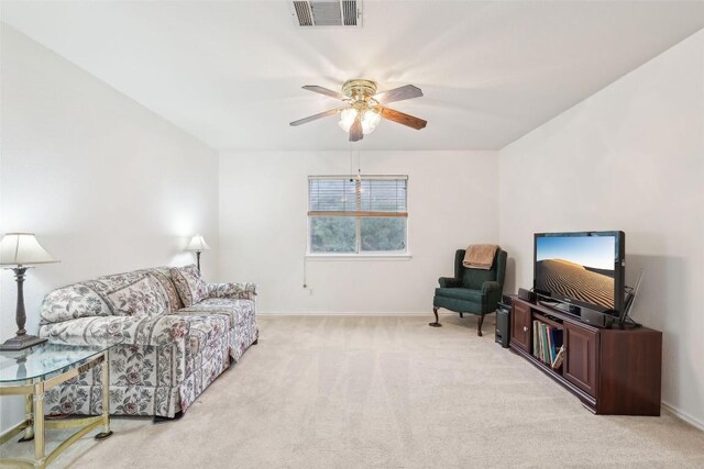 living area with baseboards, ceiling fan, light colored carpet, and visible vents