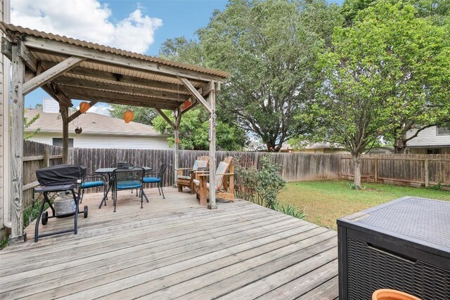 wooden terrace with a fenced backyard, a grill, a yard, and outdoor dining space