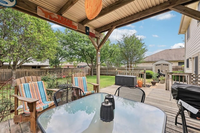 wooden deck featuring a storage shed, an outbuilding, outdoor dining area, and a fenced backyard