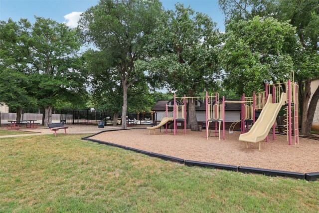 community play area featuring a lawn and fence