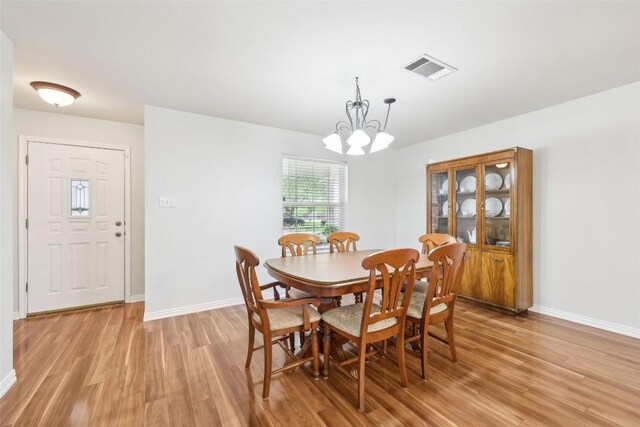 dining room with baseboards, a notable chandelier, light wood-type flooring, and visible vents