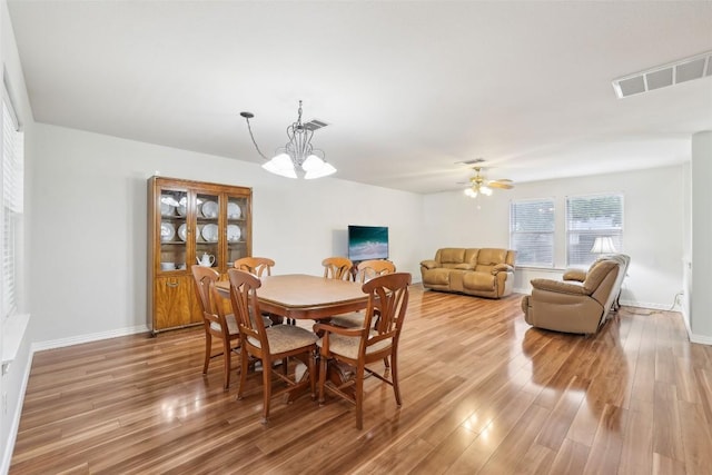 dining space with a notable chandelier, visible vents, baseboards, and light wood finished floors