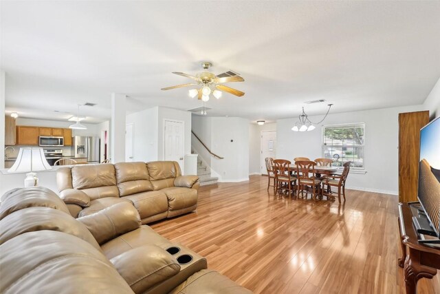 living room featuring baseboards, light wood-type flooring, stairs, and visible vents
