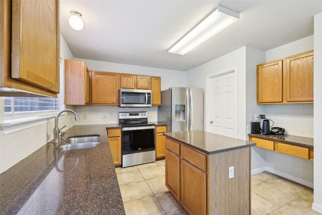 kitchen with a center island, a sink, dark stone counters, and stainless steel appliances