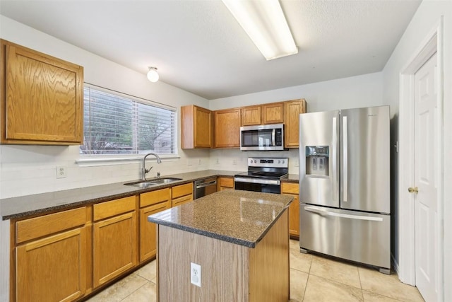 kitchen featuring a sink, dark stone counters, appliances with stainless steel finishes, and light tile patterned flooring