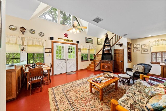 living area with visible vents, a healthy amount of sunlight, vaulted ceiling, and stairway