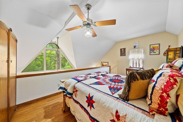 bedroom with baseboards, ceiling fan, light wood-style flooring, and lofted ceiling