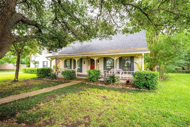 view of front of house with covered porch, brick siding, a shingled roof, and a front yard