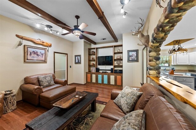 living room featuring a ceiling fan, visible vents, beam ceiling, and wood finished floors