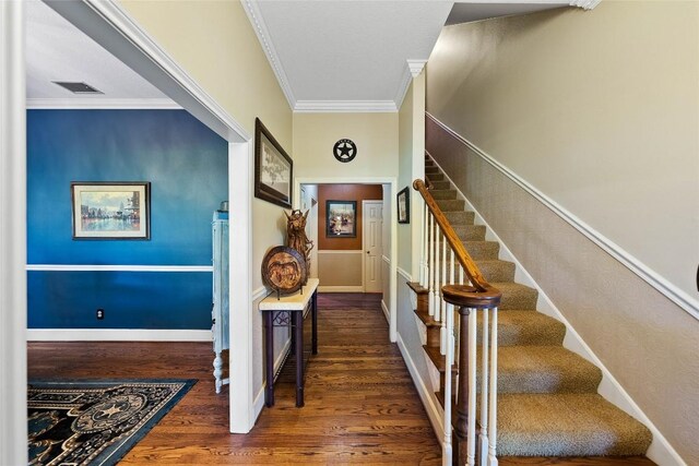 stairway featuring crown molding, baseboards, visible vents, and wood finished floors