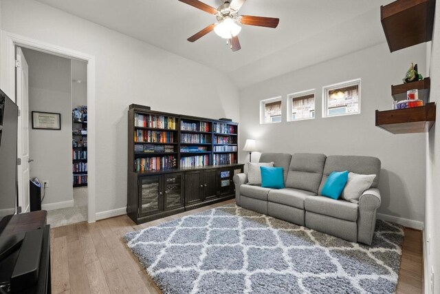 living area featuring baseboards, a ceiling fan, lofted ceiling, and wood finished floors