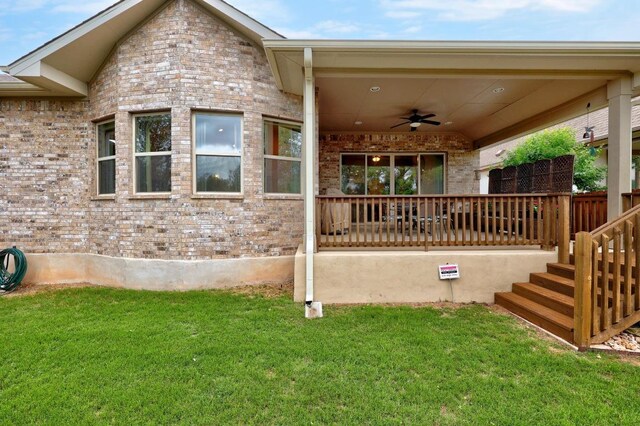 exterior space featuring a lawn, brick siding, and ceiling fan