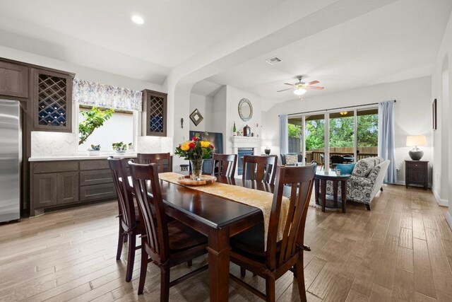 dining space featuring visible vents, a fireplace, recessed lighting, a ceiling fan, and light wood-style flooring