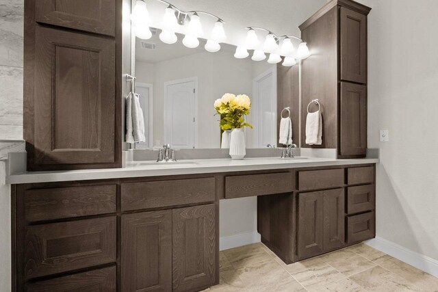 bathroom featuring a sink, baseboards, double vanity, and visible vents