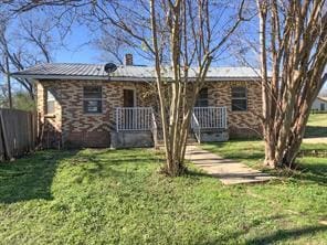 view of front of property featuring a chimney, fence, metal roof, and a front lawn