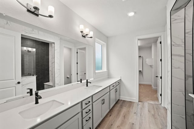 991 Hazy Hills Loop, Dripping Springs, TX 78620 - full bath with double vanity, a tile shower, a sink, and wood finished floors