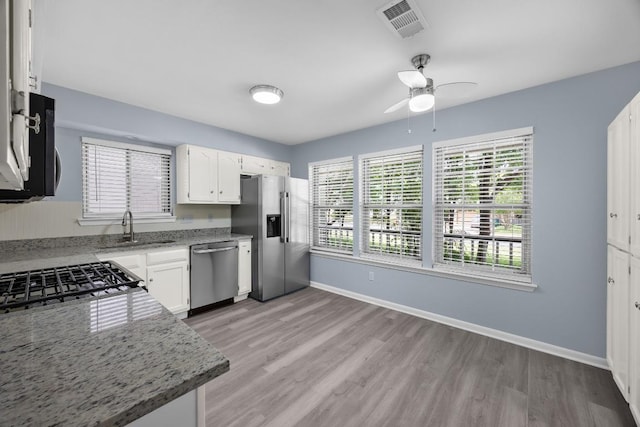 4411 Cumbria Ln, Austin, TX 78727 - kitchen featuring appliances with stainless steel finishes, light wood-type flooring, and white cabinetry