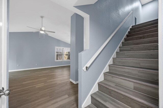 staircase with a ceiling fan, wood finished floors, lofted ceiling, and baseboards