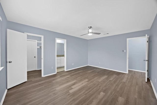 unfurnished bedroom featuring dark wood finished floors, baseboards, ceiling fan, and connected bathroom