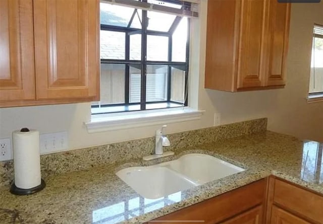 interior details featuring a sink and light stone countertops