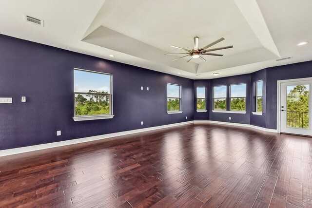 unfurnished room with a ceiling fan, a tray ceiling, wood finished floors, and visible vents