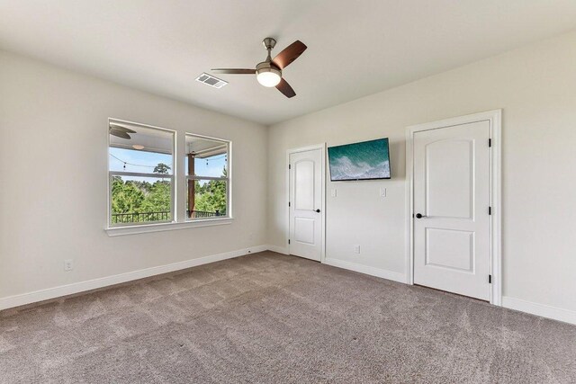 carpeted empty room featuring baseboards, a ceiling fan, and visible vents