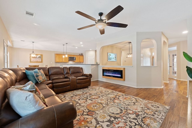 living area with visible vents, wood finished floors, baseboards, ceiling fan, and recessed lighting