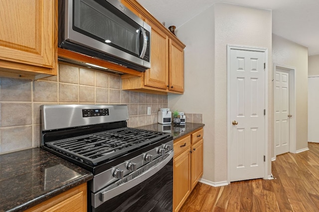 kitchen with stainless steel appliances, baseboards, decorative backsplash, and light wood-style floors