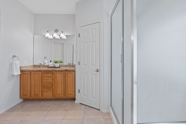 bathroom featuring double vanity, a stall shower, baseboards, and tile patterned floors