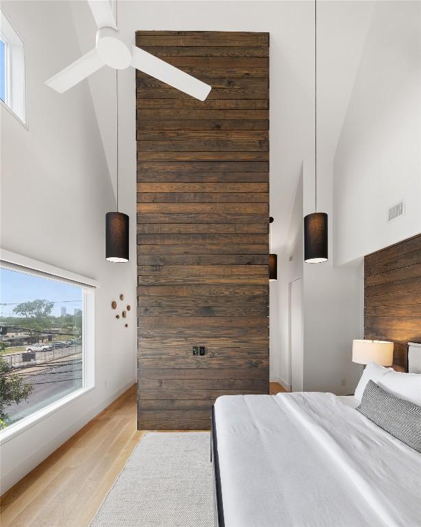 bedroom featuring visible vents, light wood-style flooring, and high vaulted ceiling
