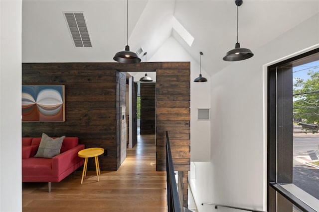 hall featuring high vaulted ceiling, visible vents, a skylight, and wood finished floors