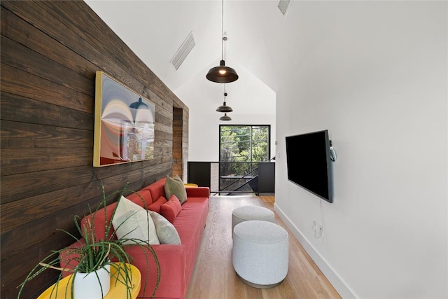 living area featuring baseboards, wood walls, wood finished floors, and visible vents