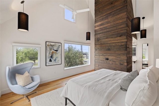bedroom with baseboards, a high ceiling, and wood finished floors
