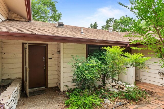 entrance to property featuring roof with shingles