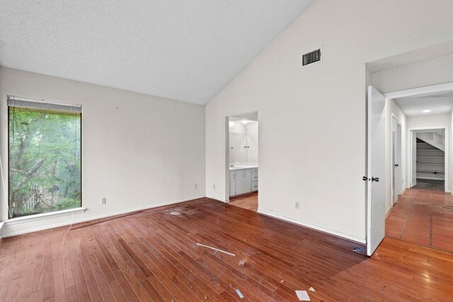spare room with high vaulted ceiling, visible vents, baseboards, and hardwood / wood-style flooring