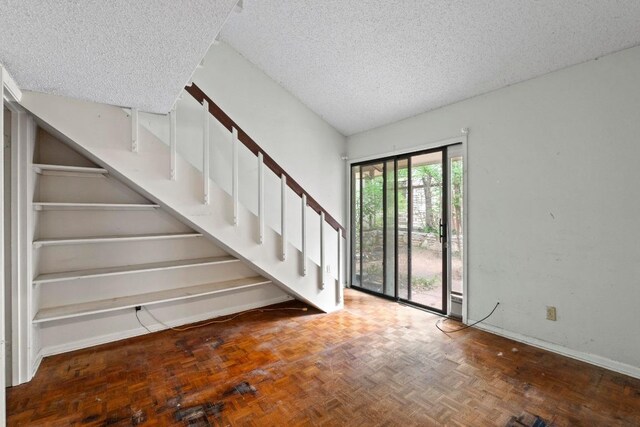 foyer with baseboards, a textured ceiling, and stairway