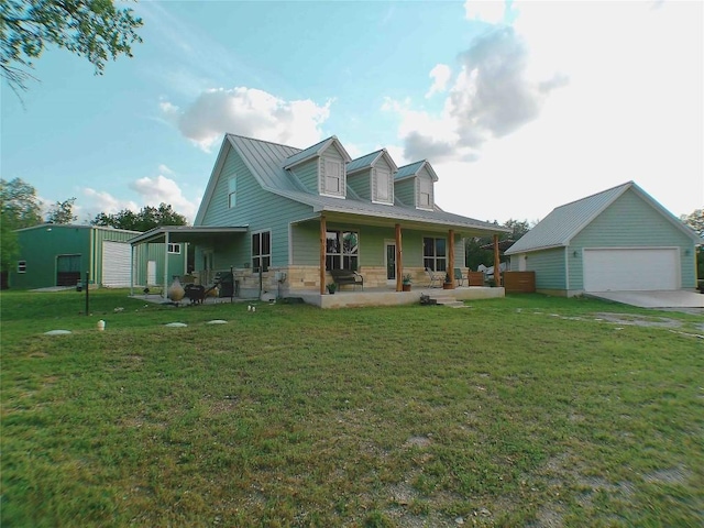 rear view of house featuring a lawn, a detached garage, an outdoor structure, and covered porch