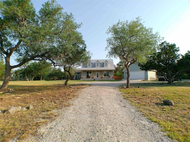 view of front of home with covered porch, an outdoor structure, gravel driveway, and metal roof