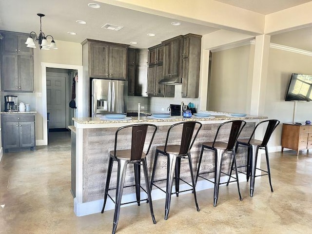 923 Debco Ln, Spicewood, TX 78669 - kitchen with stainless steel fridge, tasteful backsplash, baseboards, a breakfast bar area, and finished concrete floors