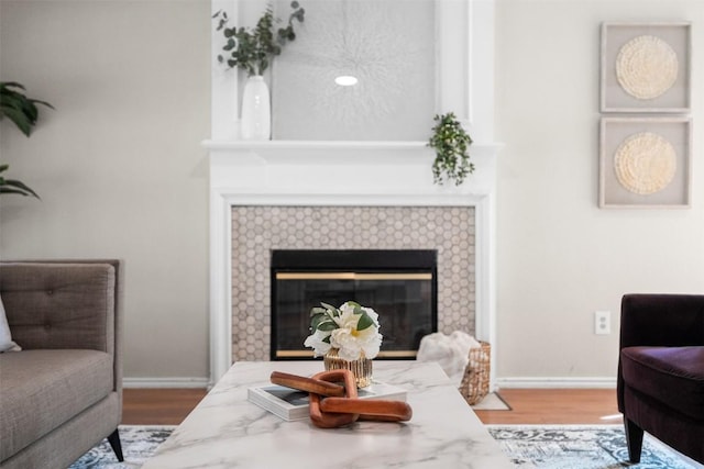 living room featuring baseboards, wood finished floors, and a tile fireplace