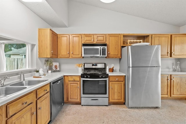 kitchen with a sink, light countertops, stainless steel appliances, and lofted ceiling