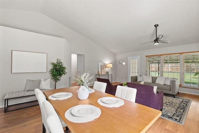 dining area with a ceiling fan, wood finished floors, and vaulted ceiling