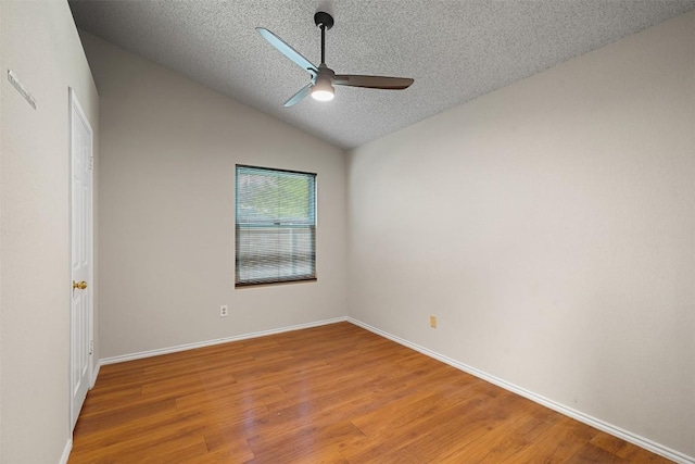 spare room featuring lofted ceiling, baseboards, ceiling fan, light wood-type flooring, and a textured ceiling