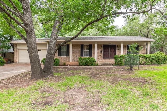 single story home with brick siding, a garage, covered porch, and concrete driveway