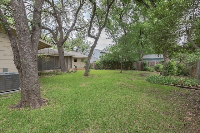 view of yard with central air condition unit, a sunroom, and fence private yard