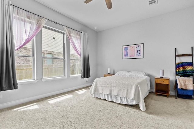 carpeted bedroom with baseboards, a ceiling fan, and visible vents