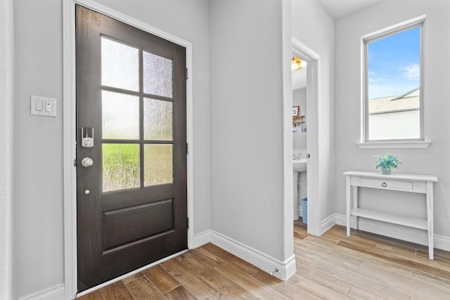 doorway featuring baseboards and light wood-style floors